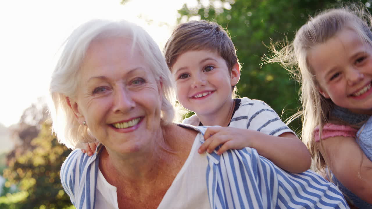 Ritratto di nonni sorridenti che portano i nipoti all'aperto in un parco estivo