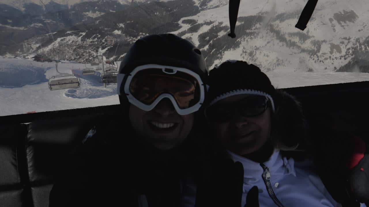 두 명의 스키 선수가 겨울에 산에서 셀카를 찍기 위해 의자 엘리베이터에 올라갑니다.