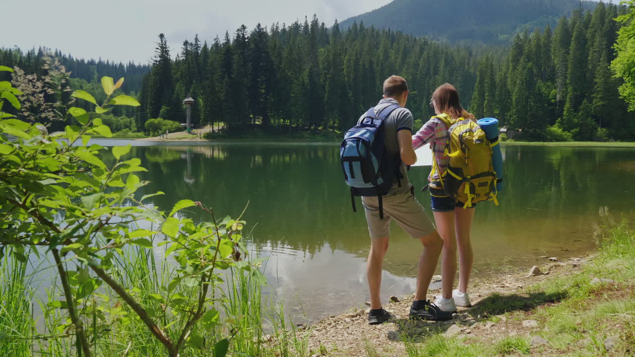 hombres y mujeres viajeros juntos se orientan en el mapa el hombre mira a través de binoculares