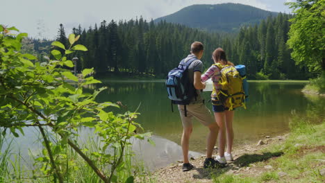 man and woman travelers together they orient themselves on the map the man looks through binoculars