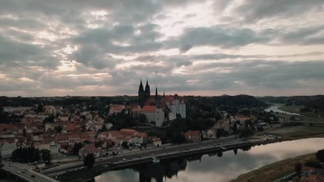 the cloudy sky reflects off the elbe river in front of the albrechtsburg castle in meissen