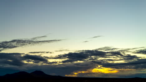 amanecer dorado sobre las llanuras del desierto de mojave con montañas en silueta mientras el paisaje de nubes se vuelve naranja - lapso de tiempo de gran angular