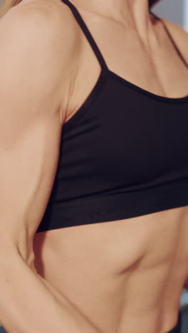 female hands are holding dumbbells and raising it to chest level on a blurred background. close-up vertical video