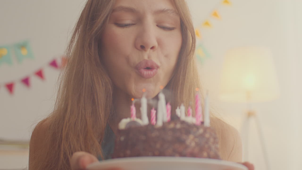 mujer apagando velas en el pastel de cumpleaños