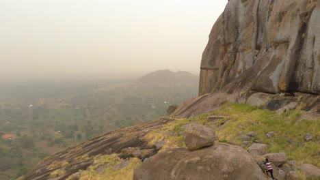 toma aérea de un joven africano escalando grandes rocas de granito en una montaña en uganda