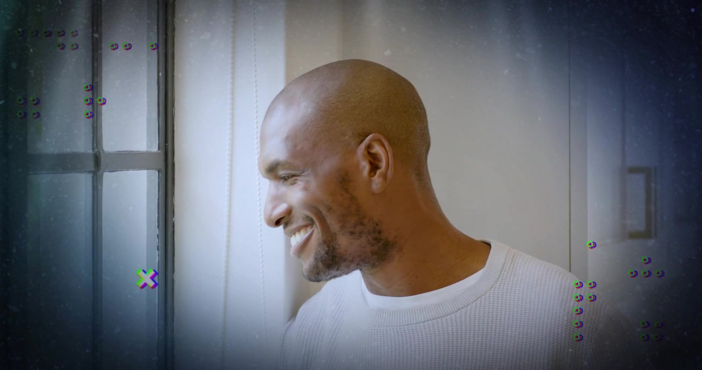 Mid adult man turning head smiling by window while tech glitch graphics appearing reflecting memory