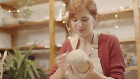 smiling female potter making earthenware bowl by hand in studio