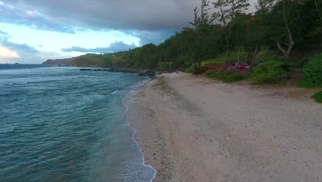 flying low above the beach near the water on the coast of maui hawaii at sunset
