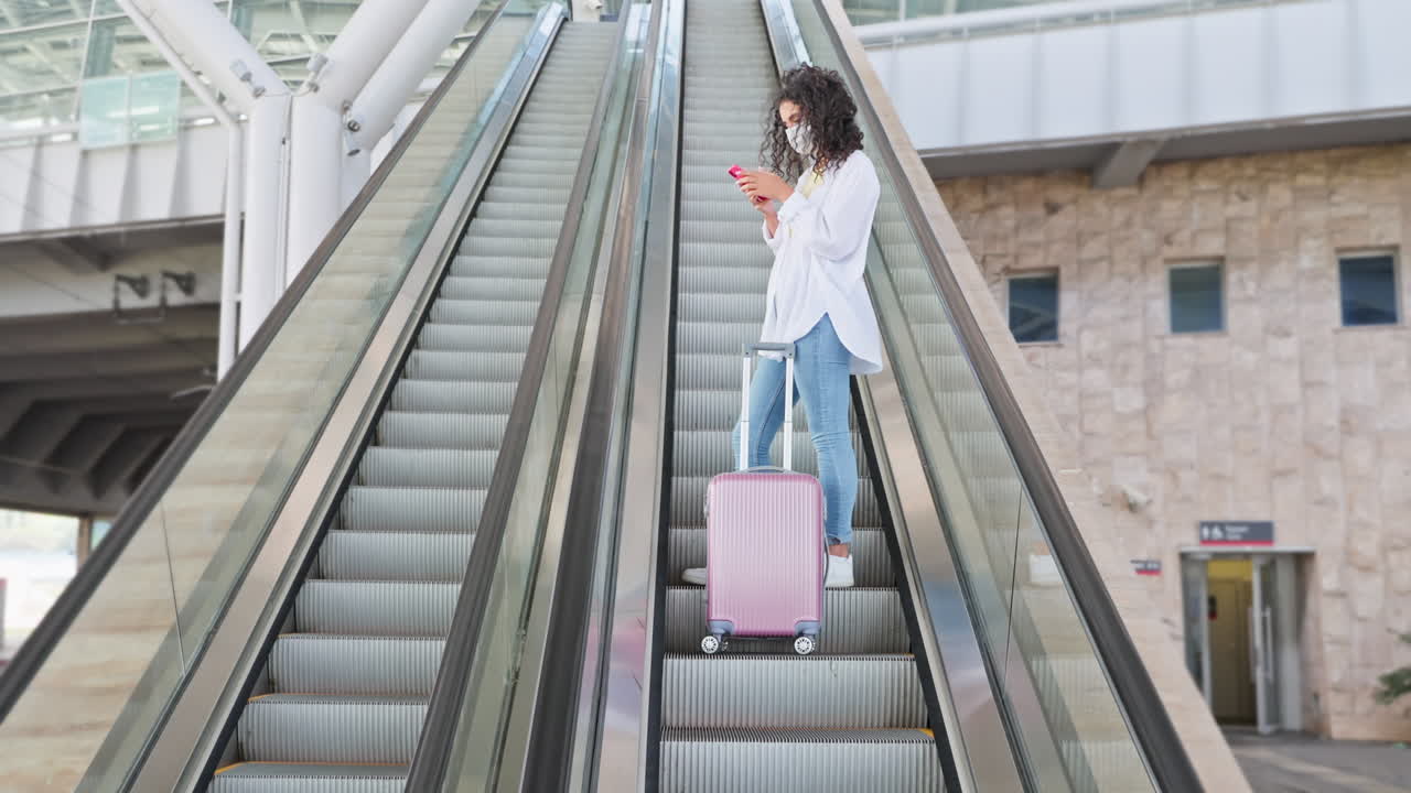 mujer usando el teléfono en la escalera mecánica en el aeropuerto