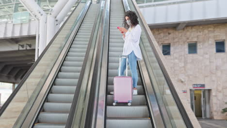 woman using phone on escalator at airport