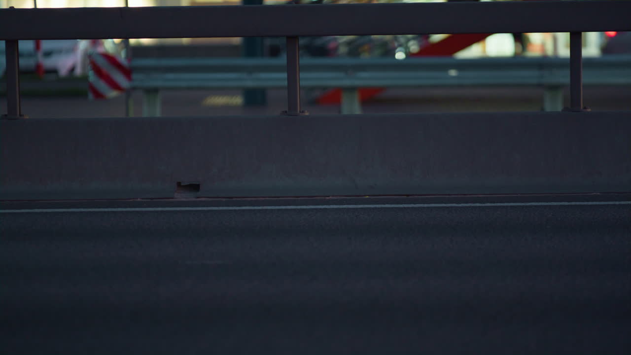 고속도로 차선을 운전하는 다양한 자동차 저녁 시간. 고속도로 충돌 장벽 전망.