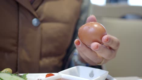 a woman is peeling a boiled egg for breakfast