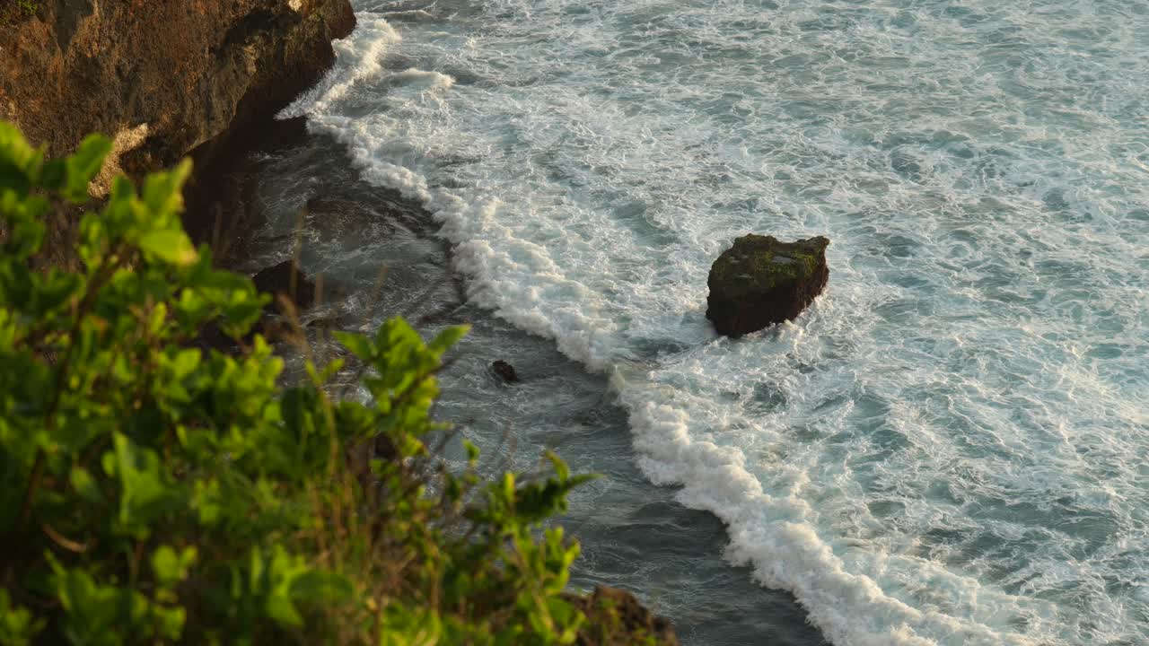 olas rompiendo sobre las rocas en cámara lenta desde la cima de un acantilado en uluwatu bali