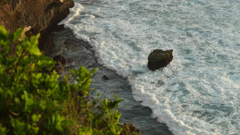 waves breaking over rocks in slow motion from the top of a cliff in uluwatu bali