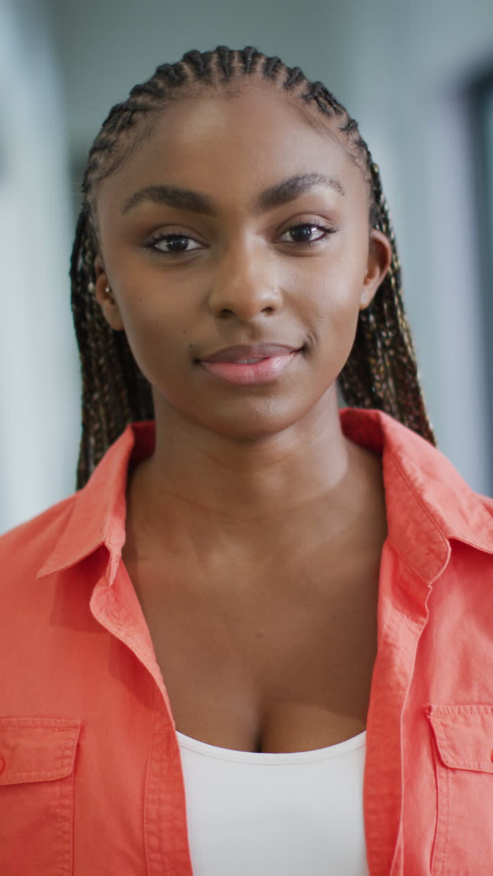Vertical video of happy african american woman looking at camera