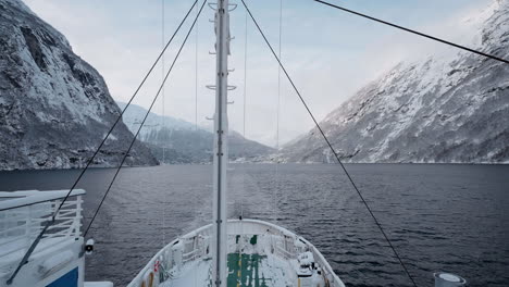 Slow-motion-POV-of-a-winter-ferry-boat-ride-in-Geirangerfjord-to-Geiranger,-Norway,-with-snowy-mountains-and-captivating-fjord-views