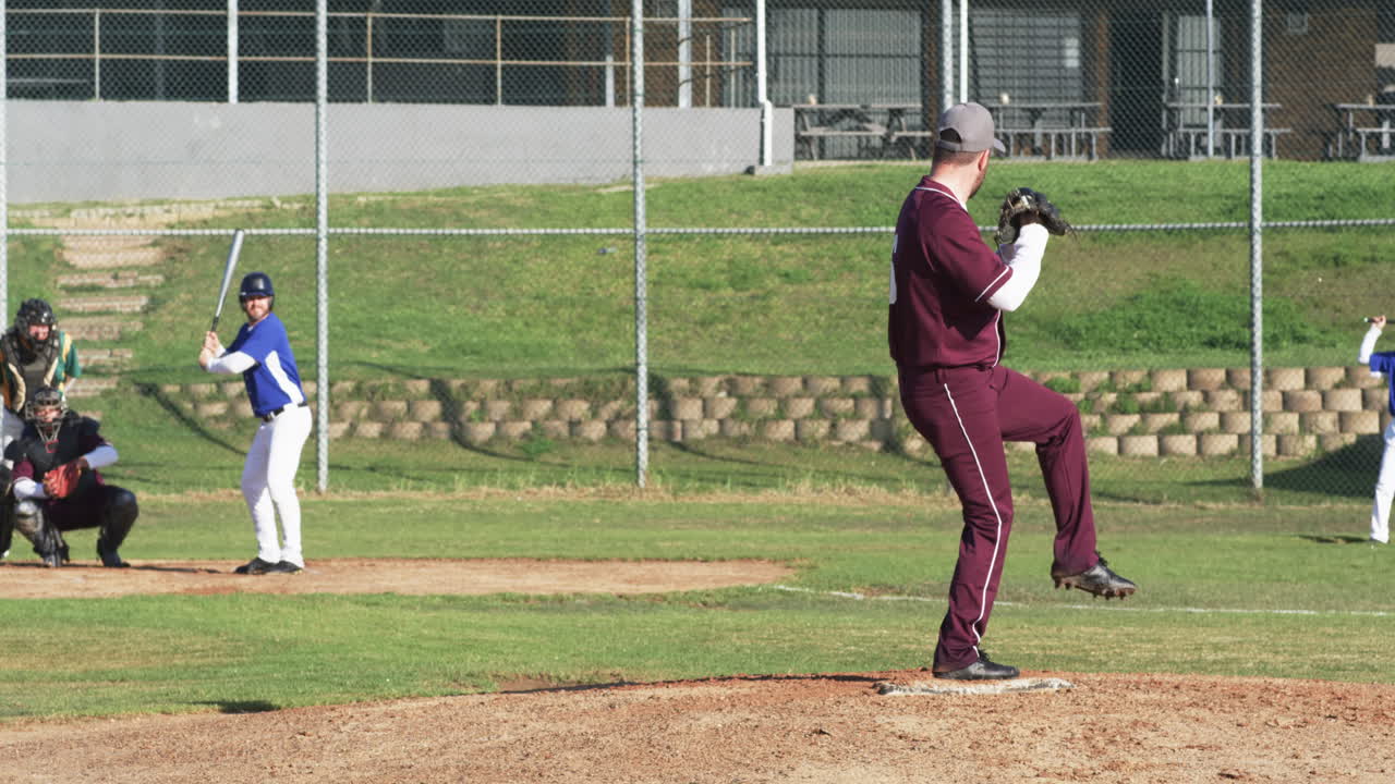 Male baseball players and umpire playing baseball, throwing the ball on a pitch, slow motion
