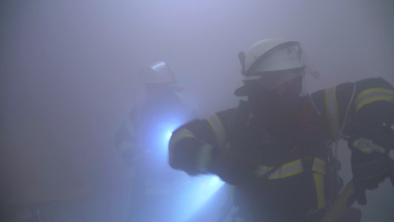 dos bomberos en una habitación oscura y ahumada