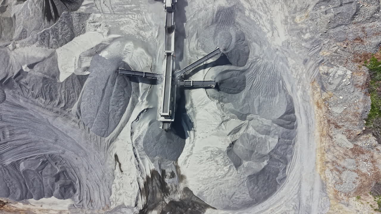 Granite quarry operation showing extraction equipment and piles of stone material during daylight hours