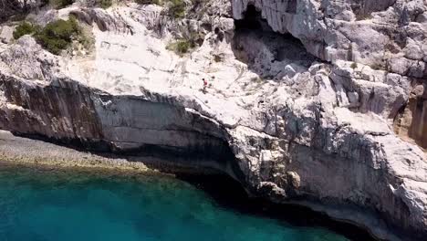 dron shot from front to top view of a guy standing on a cliff in ibiza