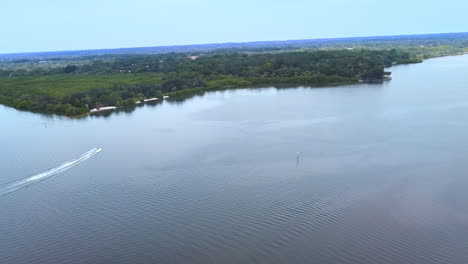 a motorized boat is moving to the shore line where a group of people enjoy a beautiful sunny day at philippe parkway, located north tampa bay area