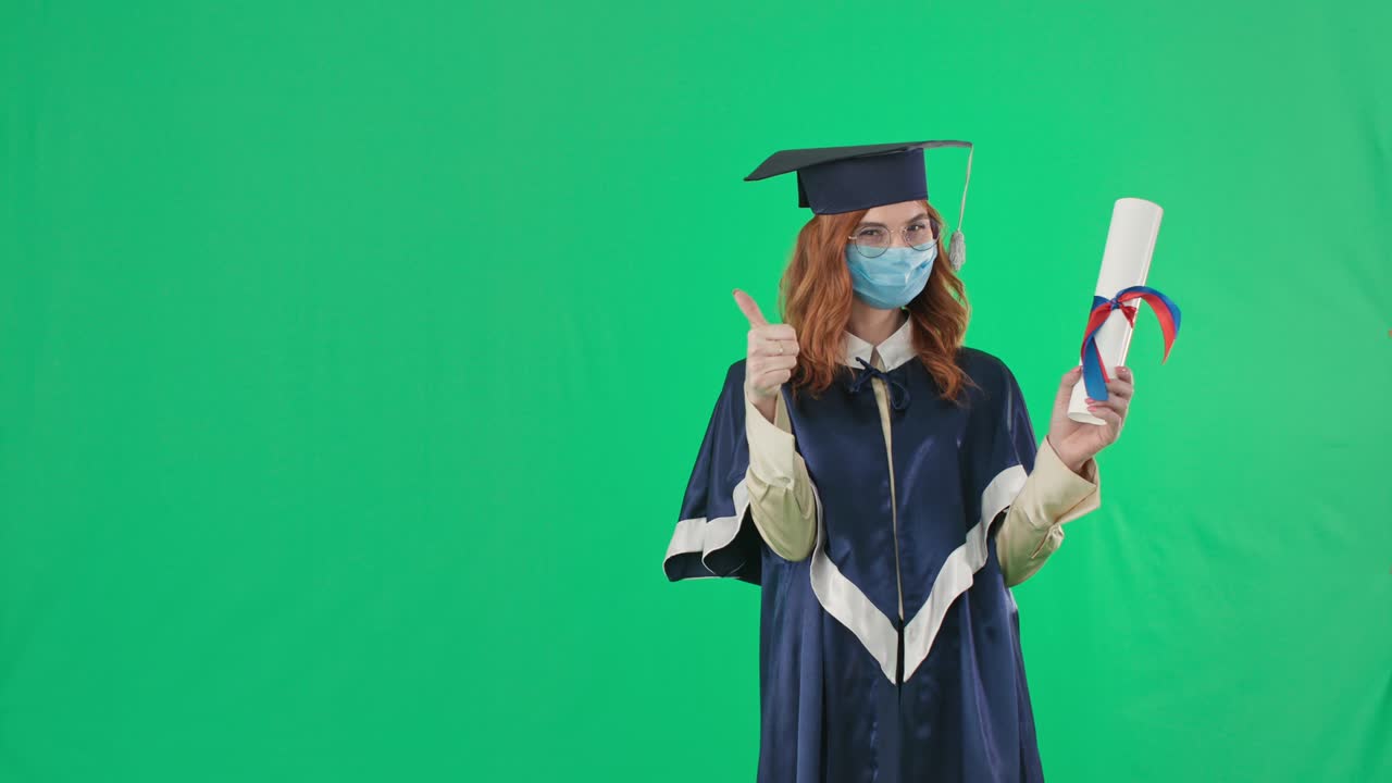 educazione in quarantena, laureata felice in abiti accademici e maschera medica mostra il diploma con il dito, poi con il dito in alto e con la mano a lato in piedi su sfondo verde, chiave croma