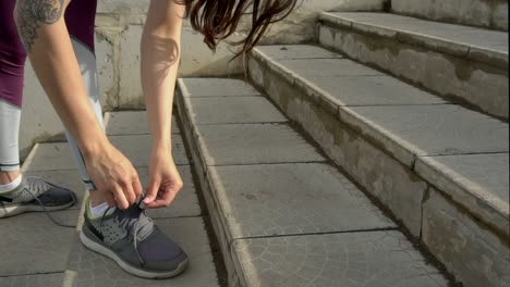 woman tying shoes on outdoor stairs