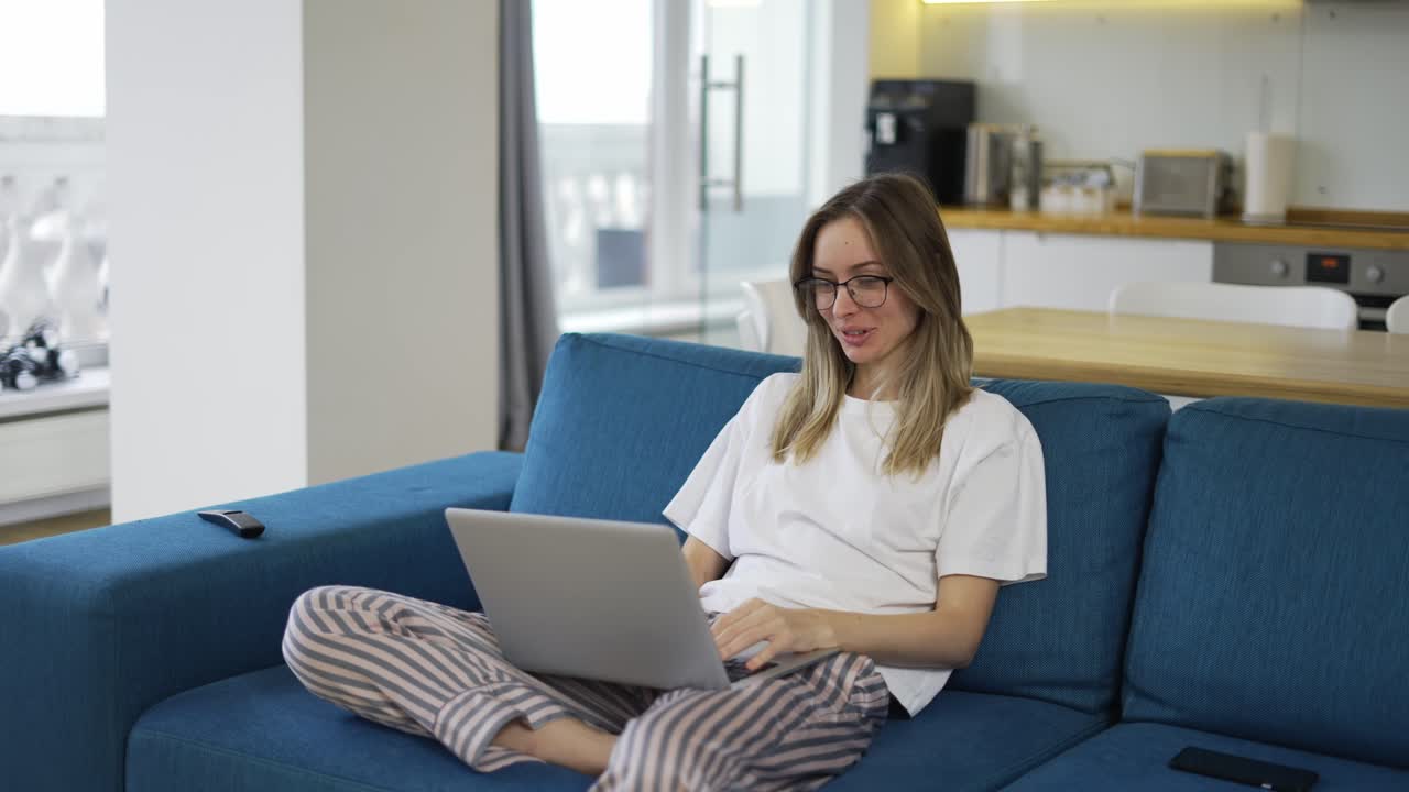 Blonde woman make video call online chat look at laptop screen sit on sofa