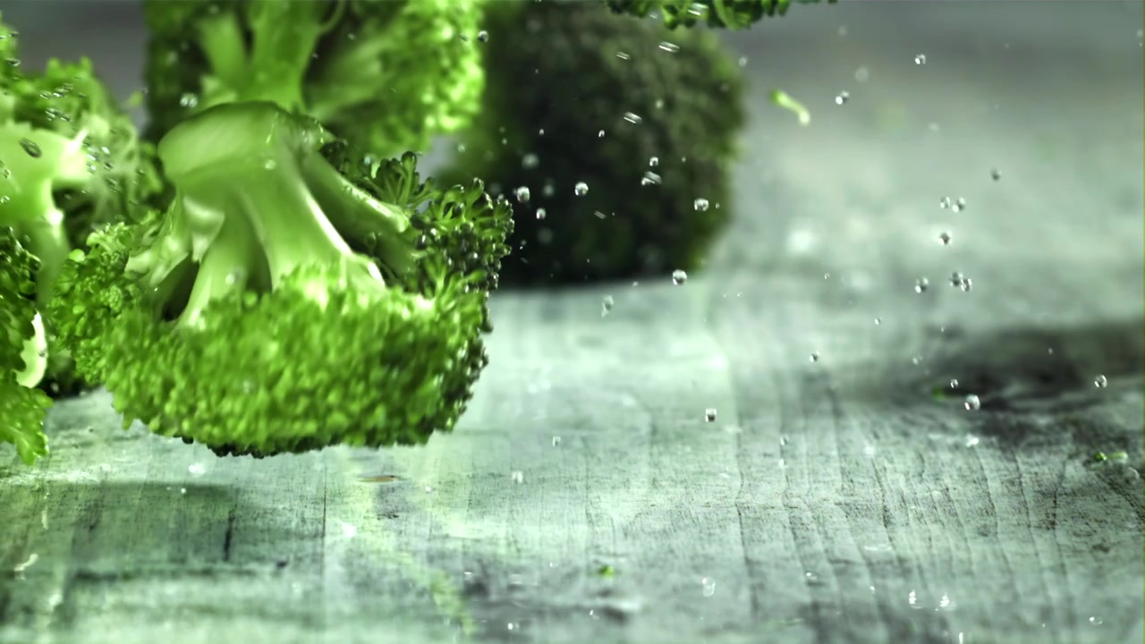 Fresh Green Broccoli Falling onto a Wet Wooden Surface in Slow Motion