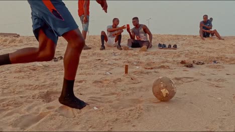 tiro bajo pateando una pelota de fútbol en la playa a la hora dorada, tiro de seguimiento