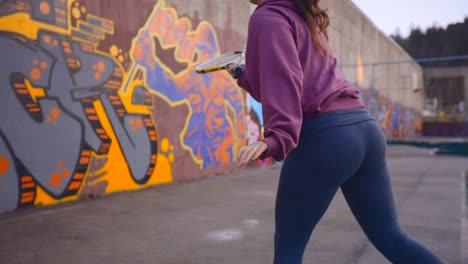 Urban-concrete-tennis-court-with-vibrant-graffiti,-a-determined-young-woman-learning-tennis