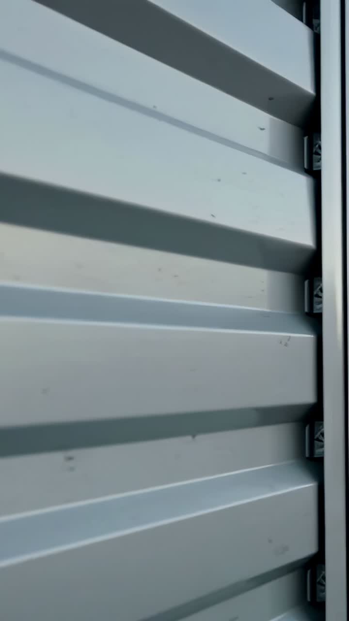 Vertical video: Shifting camera panning roll-up door at garage, showing seam, ridges and dirt marks