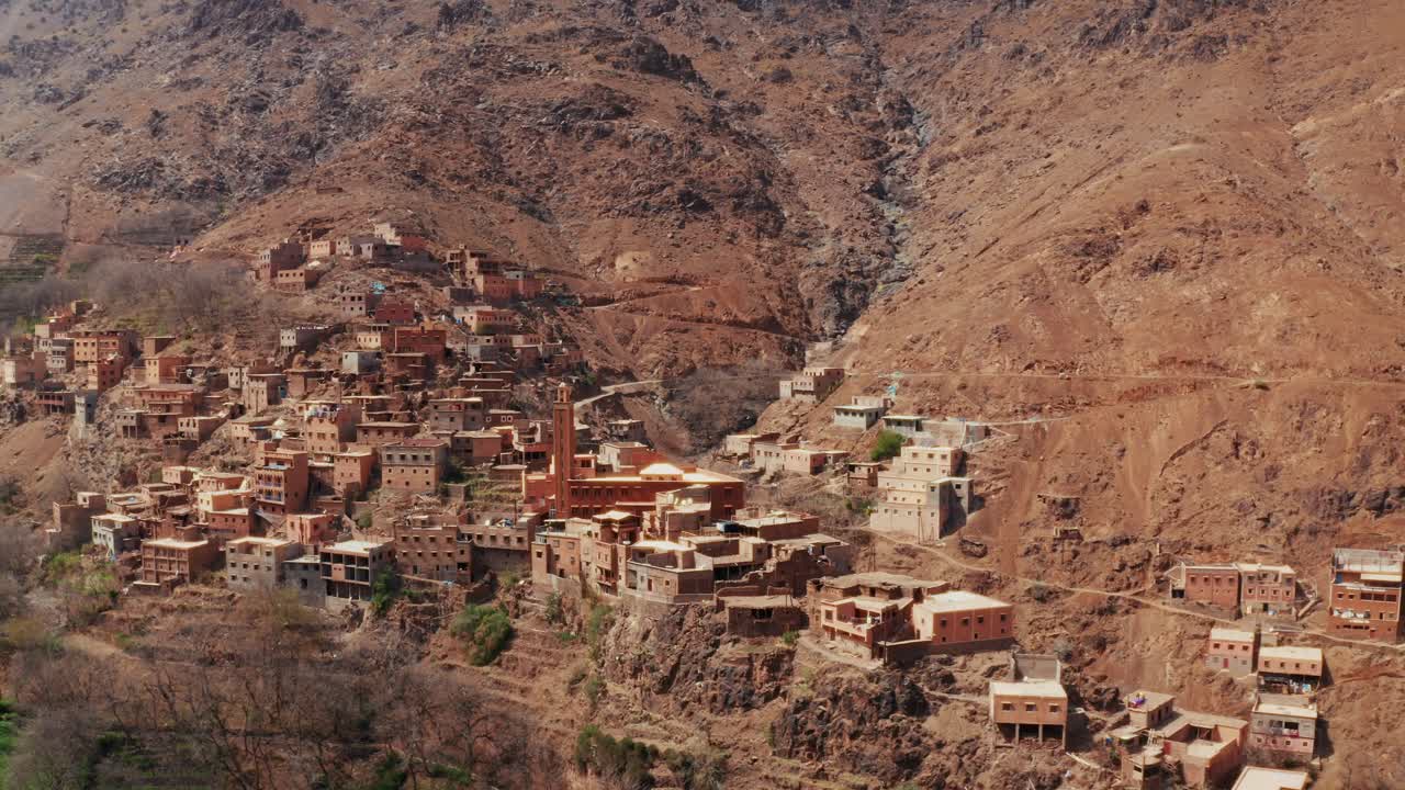 Aerial drone view of a remote rural Moroccan Village located on the High Atlas Mountains in Morocco.Camera moving backward unveiling the landscape.
