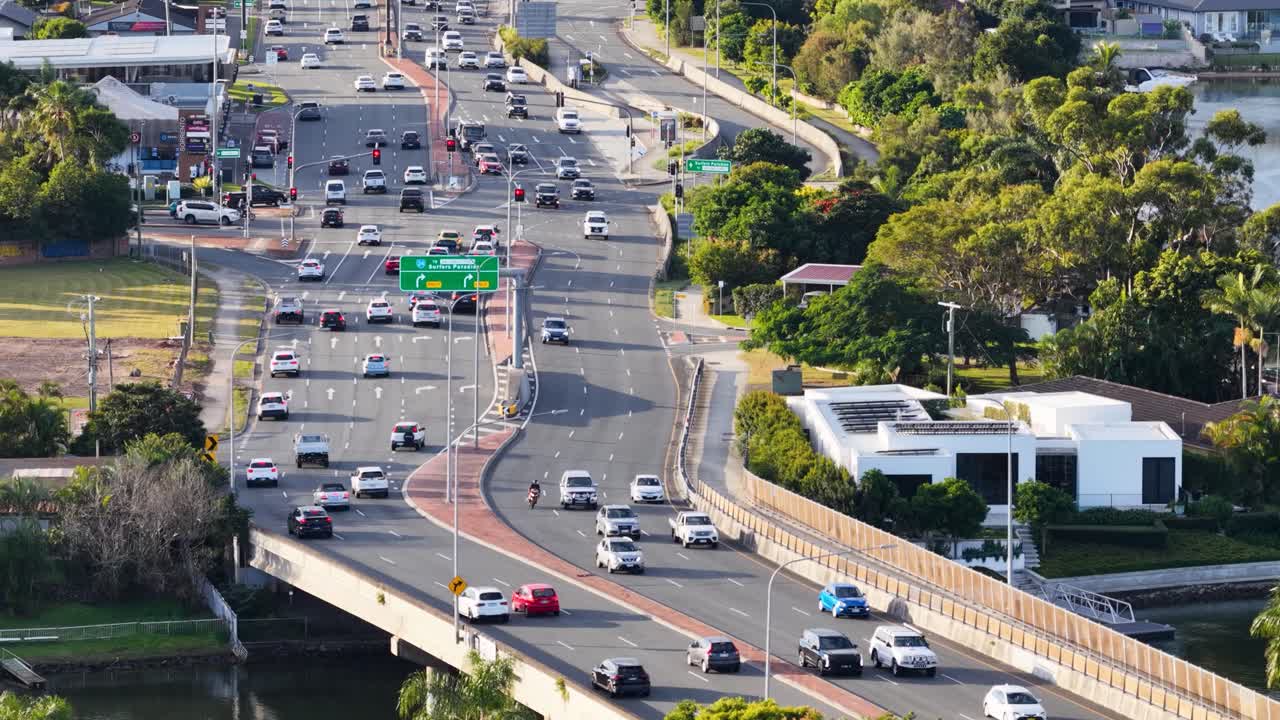 Aerial view of busy highway traffic on Gold Coast, Australia, showcasing cars, greenery, and urban landscape under bright daylight