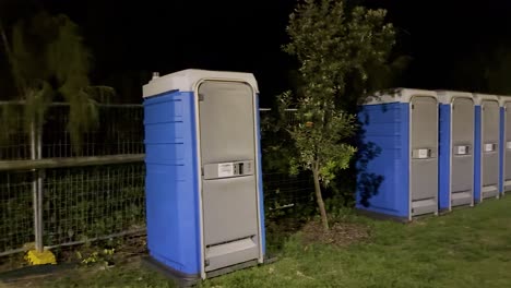 row of portable toilets under night lighting