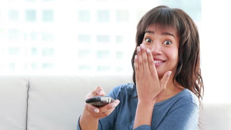 Attractive-woman-holding-a-remote-sitting-on-the-sofa