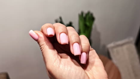 close-up of a hand with freshly manicured nail having glossy, pale pink polish