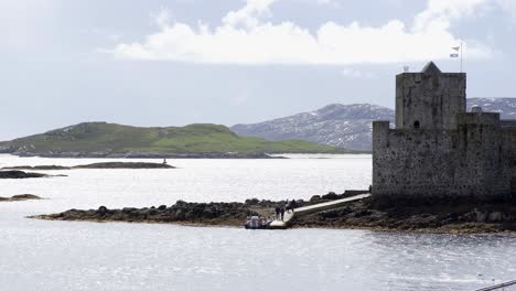 static shot of tourists disembarking their boat to kisimul castle in castlebay