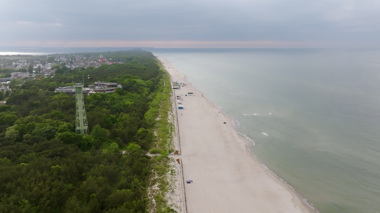 Aerial view backwards over a beach in the Hel Peninsula, cloudy sunset in Poland