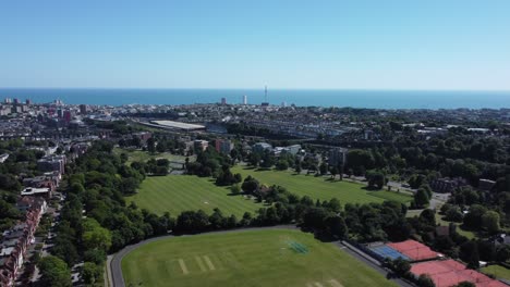 Aerial-view-of-Preston-Park,-Brighton-UK-flying-towards-the-city-and-coast-on-a-sunny-day