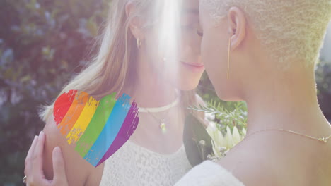 animation of rainbow heart over diverse female couple embracing