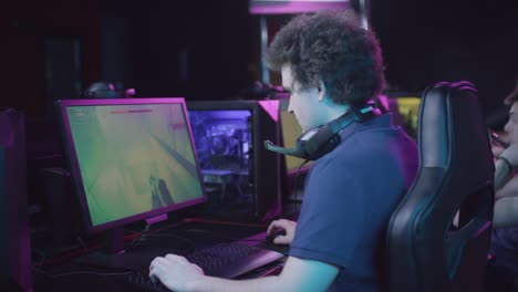 Young-Man-With-Curly-Hair-Playing-Shooter-Game-Round-In-Cybersport-Competition