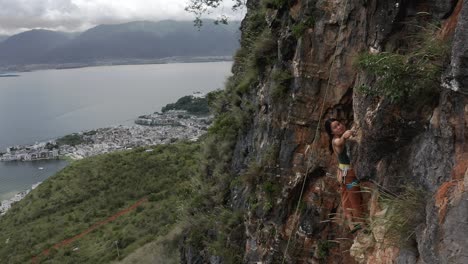 female rock climber ascending shuanglang dali rock face in china