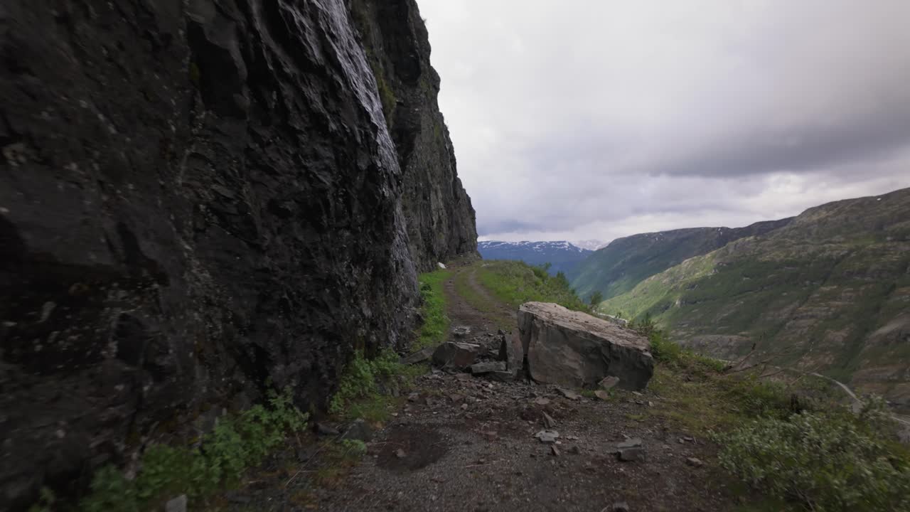 En bici por un sendero estrecho y sin asfaltar hacia Tusenmeteren: desprendimiento de rocas que bloquea una pista de tierra (plano subjetivo).
