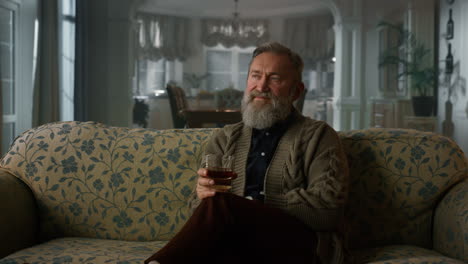 senior man drinking cognac in the living room