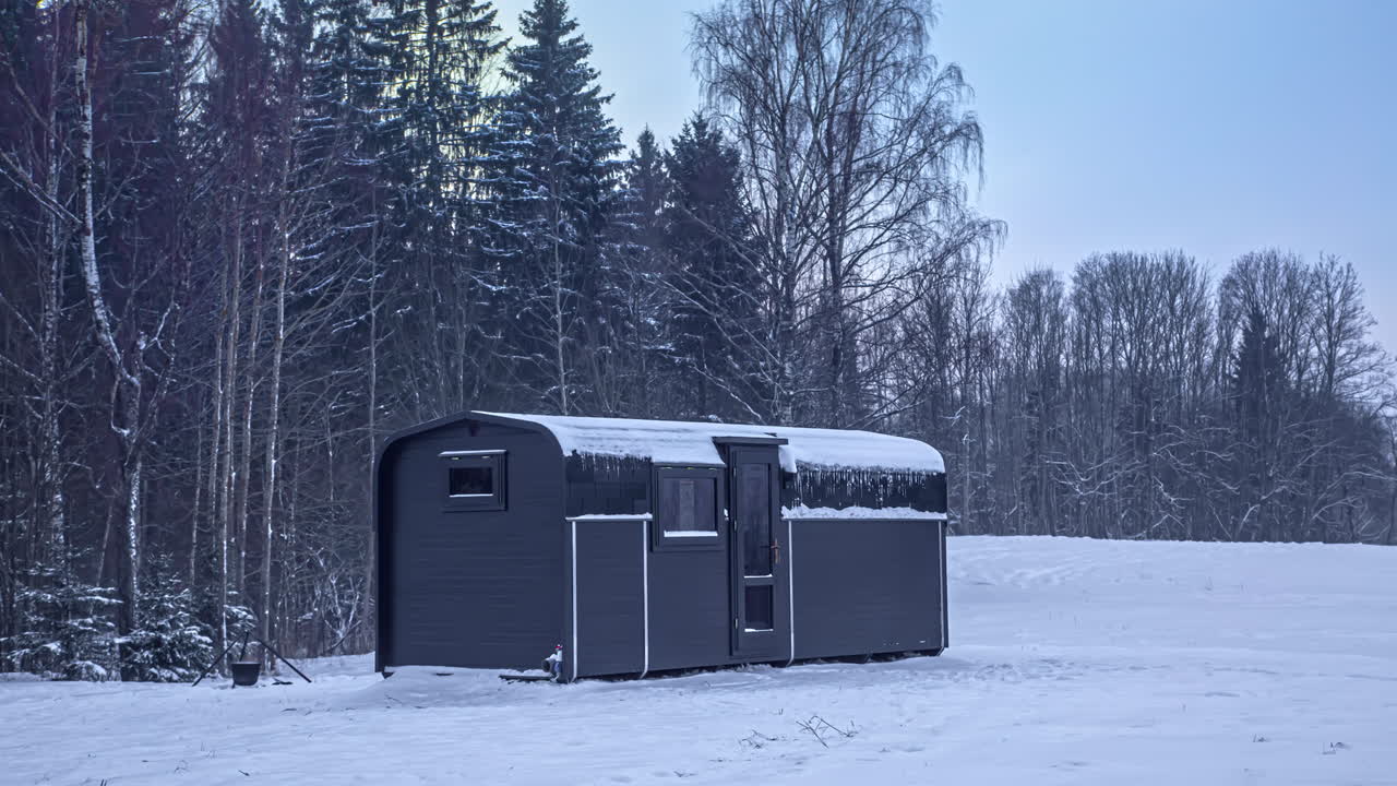 Black Cabin in Snowy Forest at Sunset