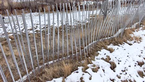 aluminum tubes wind along a trail in rows like prison bars.