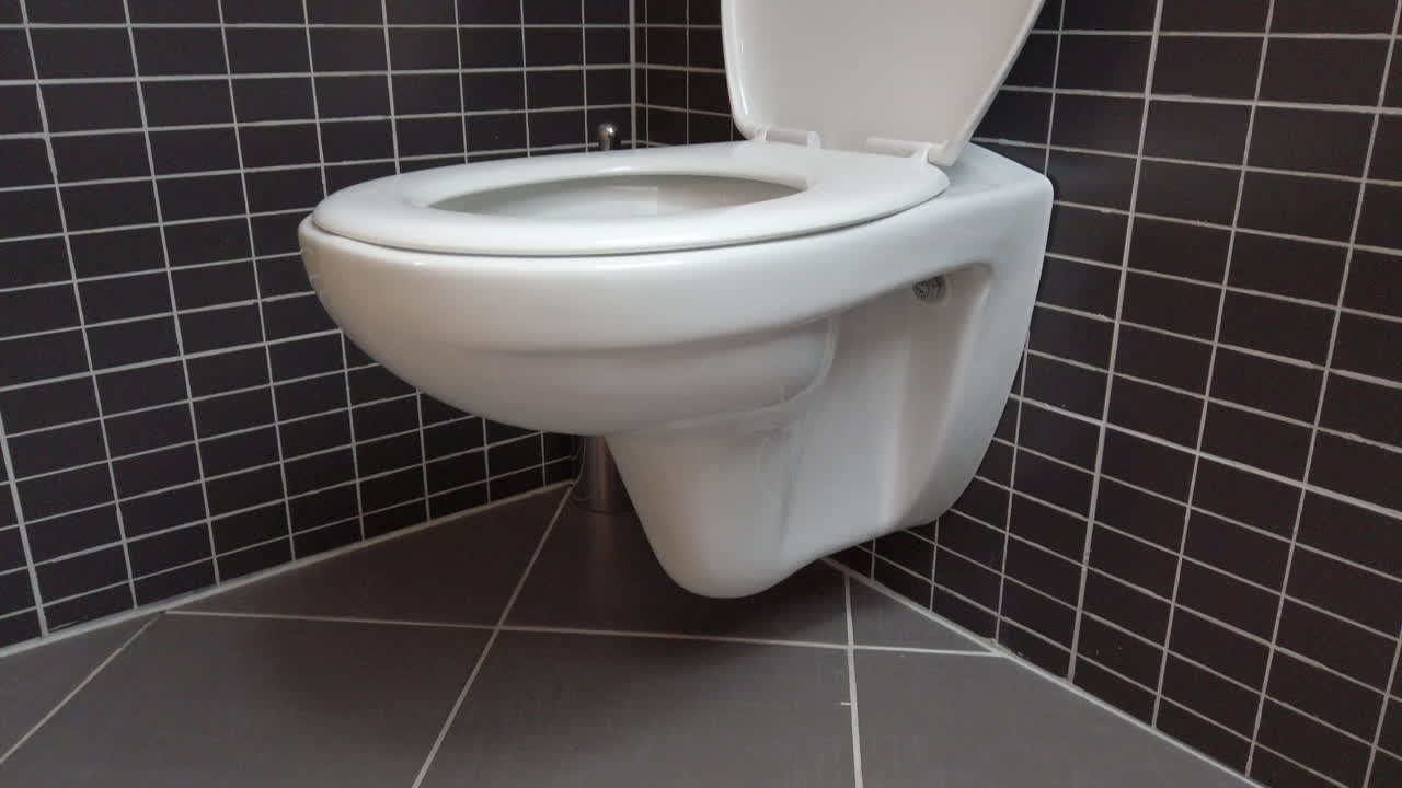 taza del inodoro, lavabo en un baño moderno con azulejos negros y grises, 4k uhd, tiro rápido inclinado hacia arriba, tapa abierta, blanco sobre fondo negro