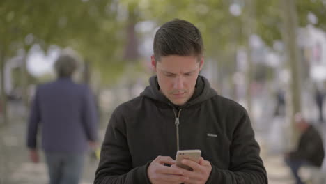 Hombre-Enfocado-Usando-Teléfono-Inteligente-Y-Riendo-Al-Aire-Libre