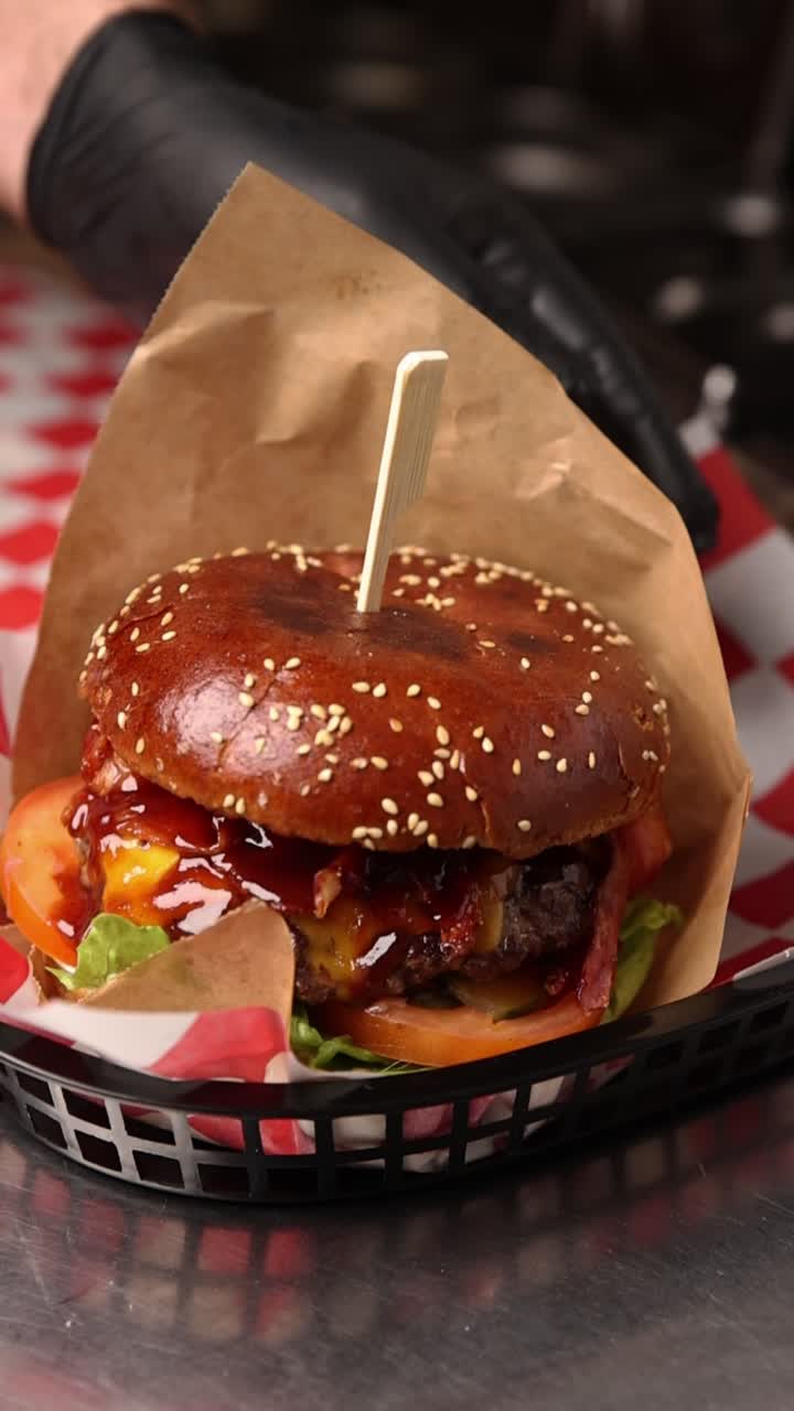 Chef's Hand Placing a Gourmet Cheeseburger into a Basket